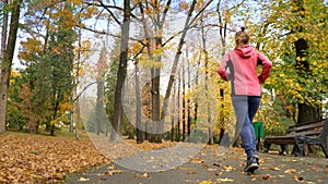 Athletic young girl running in autumn Park after rain. rear view