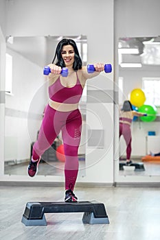 Athletic young girl training with dumbbells in the gym. The concept of sports, a healthy lifestyle, losing weight