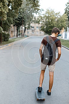 Athletic young handsome hipster man in trendy summer clothes with a black backpack rides snowboarding. Fashionable guy