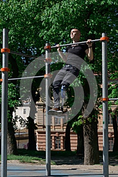 athletic young man with artificial leg working out on a bars