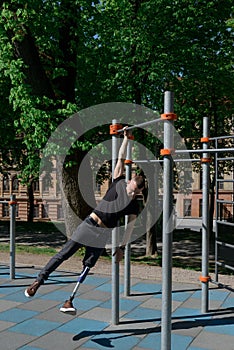 athletic young man with artificial leg working out on a bars