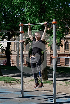 athletic young man with artificial leg working out on a bars