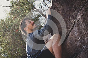 Athletic young man climbing rock mountain outdoors