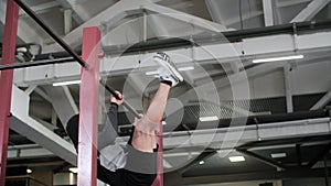 Athletic young man doing ABS exercises on bar in gym