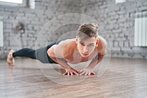 Athletic young man doing push ups on the floor