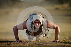 Athletic young man exercising outdoor on dusty field