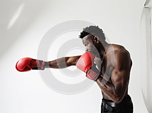 Athletic young man with good physique body condition boxing with red gloves.