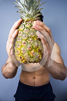 Athletic young man holding a fresh pineapple