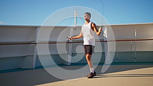 Athletic young man jumping rope outside on cruise ship open deck