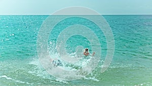 Athletic Young man jumps into the sea with clear blue water while girl swimming