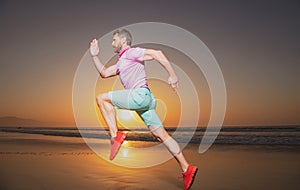 Athletic young man running in the nature. Fit man fitness model working outdoor by sea beach. Dynamic run movement.