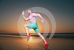 Athletic young man running in the nature. Fit man fitness model working outdoor by sea beach. Dynamic run movement.