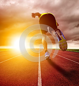 Athletic young man running on race track with sunset background