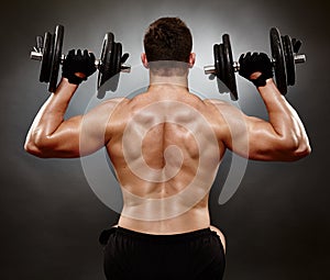 Athletic young man working with heavy dumbbells photo