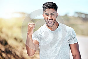 Athletic young mixed race man celebrating during outdoor exercise. Handsome hispanic male doing a fist pump and cheering