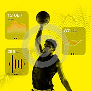 Athletic young muscular man, basketball player in motion, playing against yellow background with health tracking