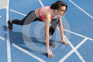 Athletic young runner on starting line at running track stadium