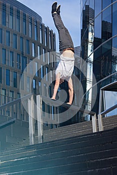 Athletic young street tracer handstanding in the city