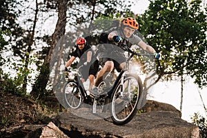 athletic young trial bikers riding on rocks