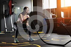 Athletic young woman doing crossfit exercises with a rope.