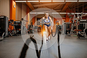 Athletic young woman doing crossfit exercises with a rope.