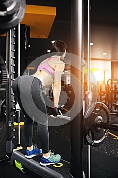 Athletic young woman doing deadlift exercise in the smith machine.