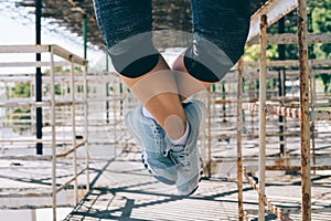 Athletic young woman doing pull-ups in the morning outdoors, close-up