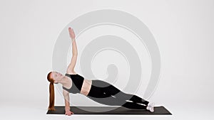Athletic Young Woman Doing Side Plank Rotations Exercise While Training In Studio