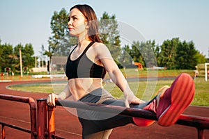 Athletic young woman doing warm-up on sports field