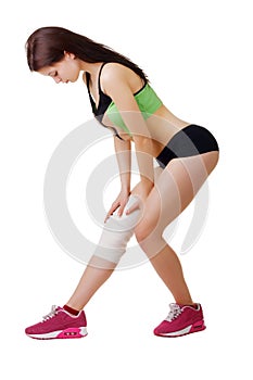 Athletic young woman with elastic bandage on his leg. Isolated