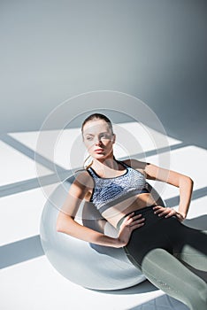 athletic young woman exercising with fitness ball and looking away