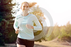 Athletic young woman jogging, running and training outdoors on a sunny day in summer