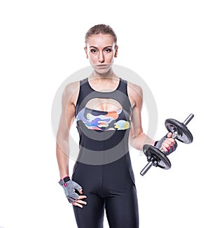 athletic young woman with perfect strong muscular body wearing sportswear tracksuit pumping up muscles with dumbbells