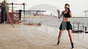 Athletic young woman shadow boxing by the sea. Beautiful female boxer training on the beach in the morning, throwing