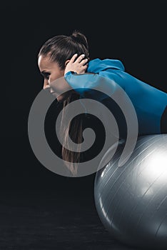 Athletic young woman in sportswear exercising with fitness ball