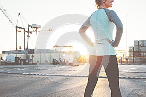 Athletic young woman standing in industrial area. Resting after nice workout. Sporty and fit body