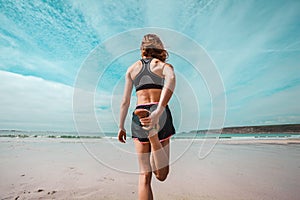 Athletic young woman stretching on the beach