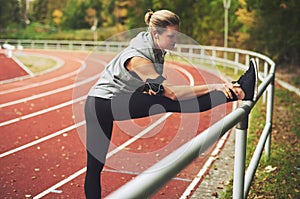 Athletic young woman stretching on stadium photo