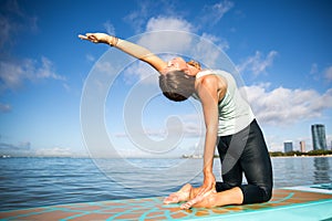 Athletic young woman in SUP Yoga practice back bend Pose in Ala photo