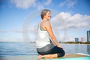 Athletic young woman in SUP Yoga practice relaxing on her paddle photo