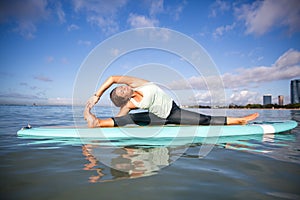 Athletic young woman in SUP Yoga practice side bend Pose in Ala