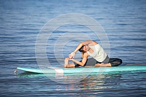 Athletic young woman in SUP Yoga practice side bend Pose in Ala