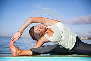 Athletic young woman in SUP Yoga practice side bend Pose in Ala photo