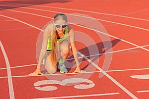 Athletic young woman on the track of the stadium preparing for the start, starting to run