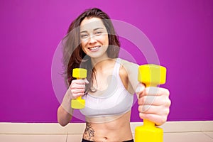 Athletic young woman works out with pink dumbbells