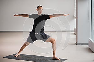 An athletically built man does yoga in the gym on a mat