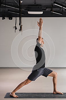 An athletically built man does yoga in the gym on a mat