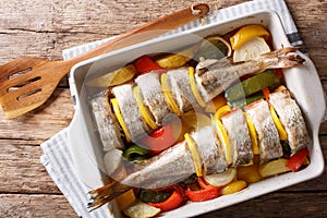 Atlantic cod baked with vegetables in a baking dish close up. Ho