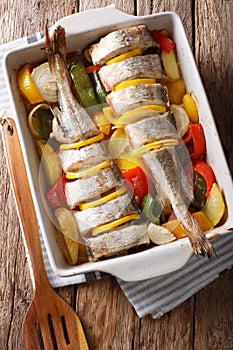 Atlantic cod baked with vegetables in a baking dish close up. Vertical top view