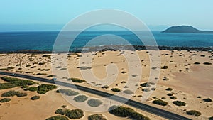 Atlantic ocean azure waves. Aerial view of highway road, Corralejo sand beach, outskirts. Aerial landscape of city. Road